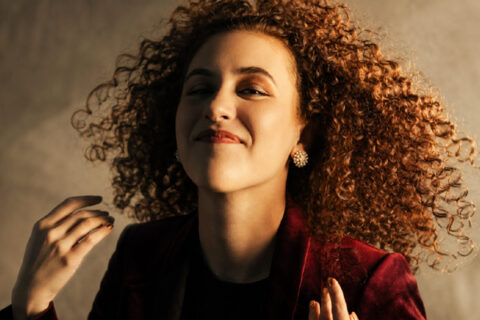 Gabrielle Lovelace wearing a deep red jacket with her curly hair in motion.