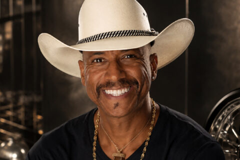 Knolly Williams in a cowboy hat with a glossy late-1990s rap-inspired backdrop.