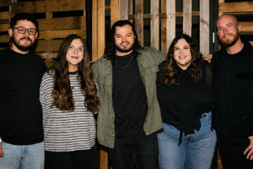 Members of Madison Street Worship standing together in front of a wooden backdrop.
