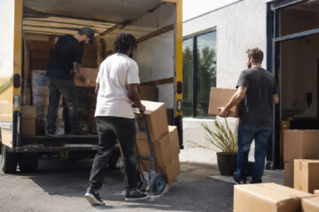 Team members unload boxes from a moving truck during a company office relocation.
