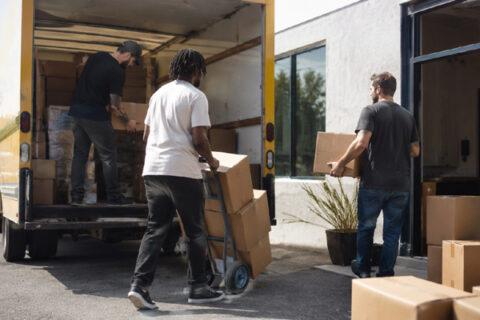 Team members unload boxes from a moving truck during a company office relocation.