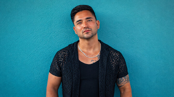Sean Rodriguez standing against a teal wall in a black shirt.