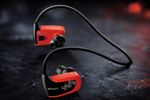Red Sony Walkman W Series waterproof MP3 player headphones on a dark textured surface.