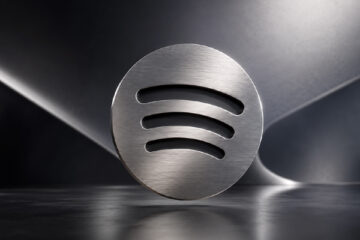 Three-dimensional platinum Spotify mark centered over a sleek metallic abstract background.