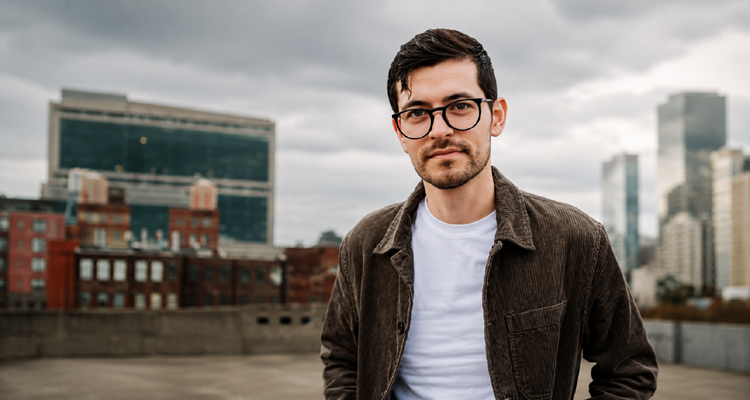 David Radford of The Gray Havens standing on a rooftop with a city skyline behind him.